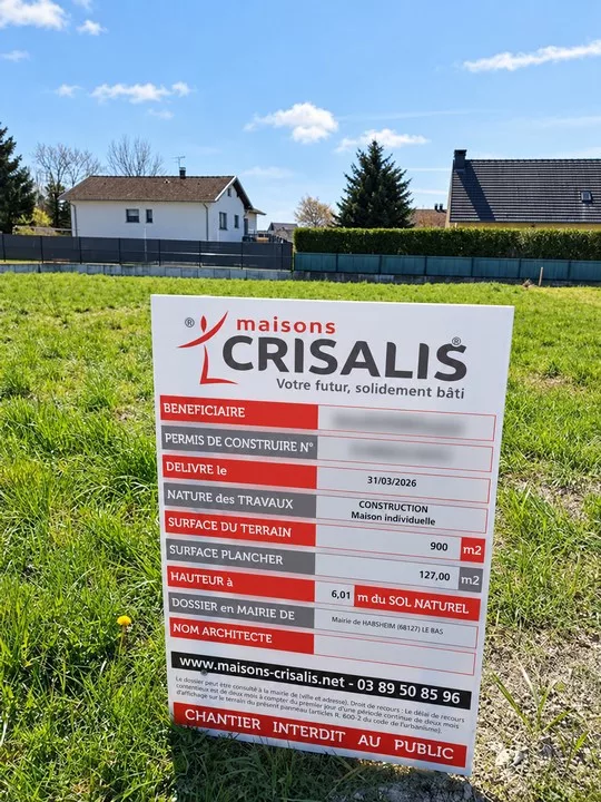 panneau de permis de construire Maisons Crisalis installé sur un terrain avant les travaux