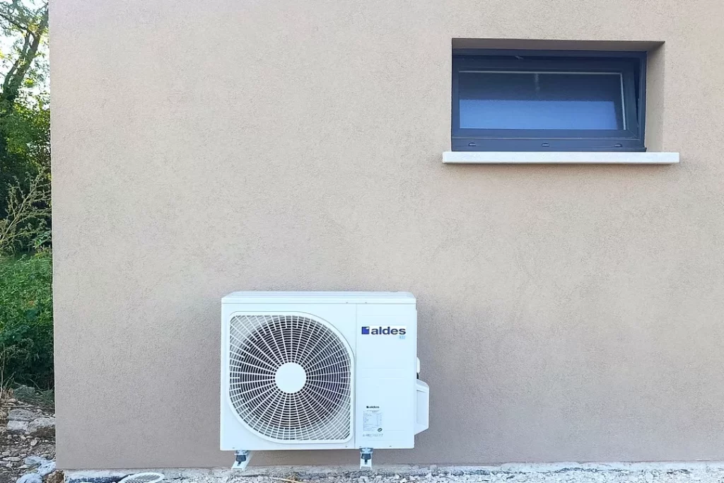 Unité extérieure de pompe à chaleur Aldes installée au pied de la façade d’une maison