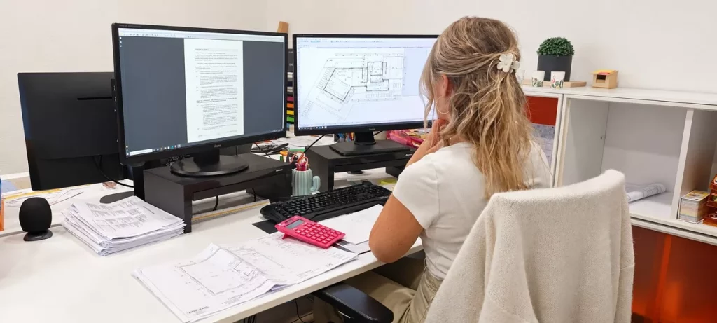 Collaboratrice Maisons Crisalis travaillant sur les plans d’une maison et son dossier de permis de construire